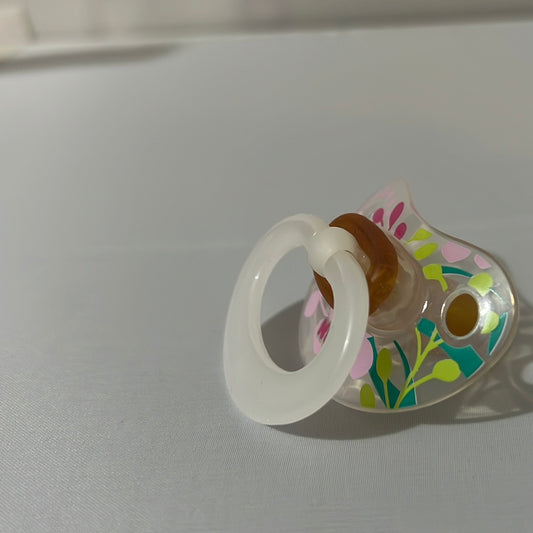 Translucent NUK Pacifier with floral pattern.