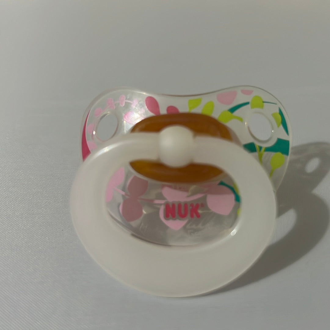 Translucent NUK Pacifier with floral pattern.